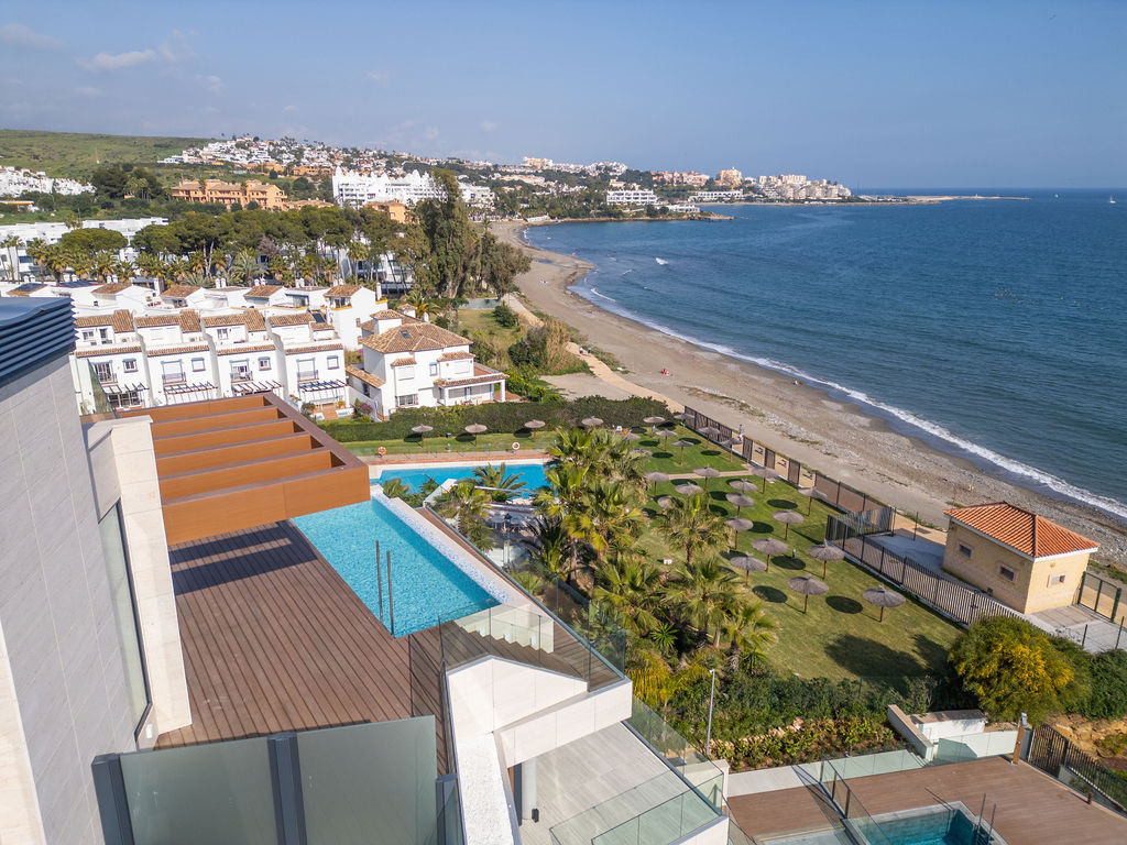 High angle view of a rooftop deck with an infinity pool, overlooking a beach and town.