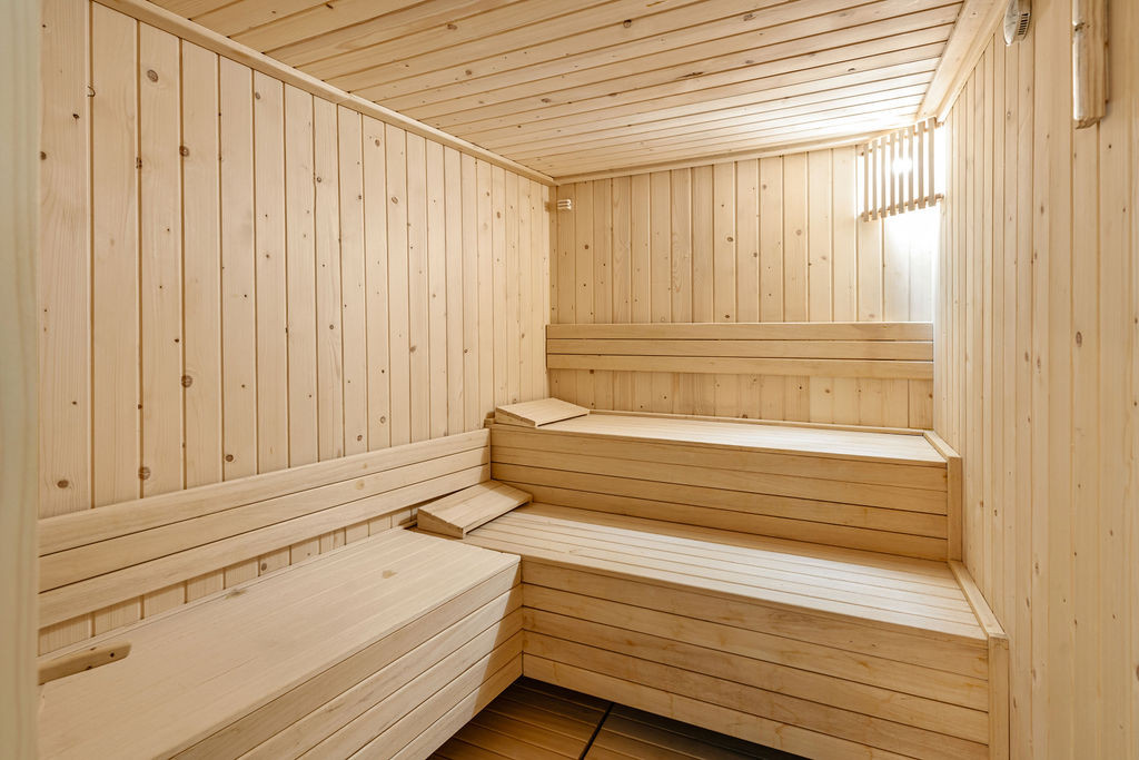 Interior of a wooden sauna room with multiple tiers of benches and slatted walls.
