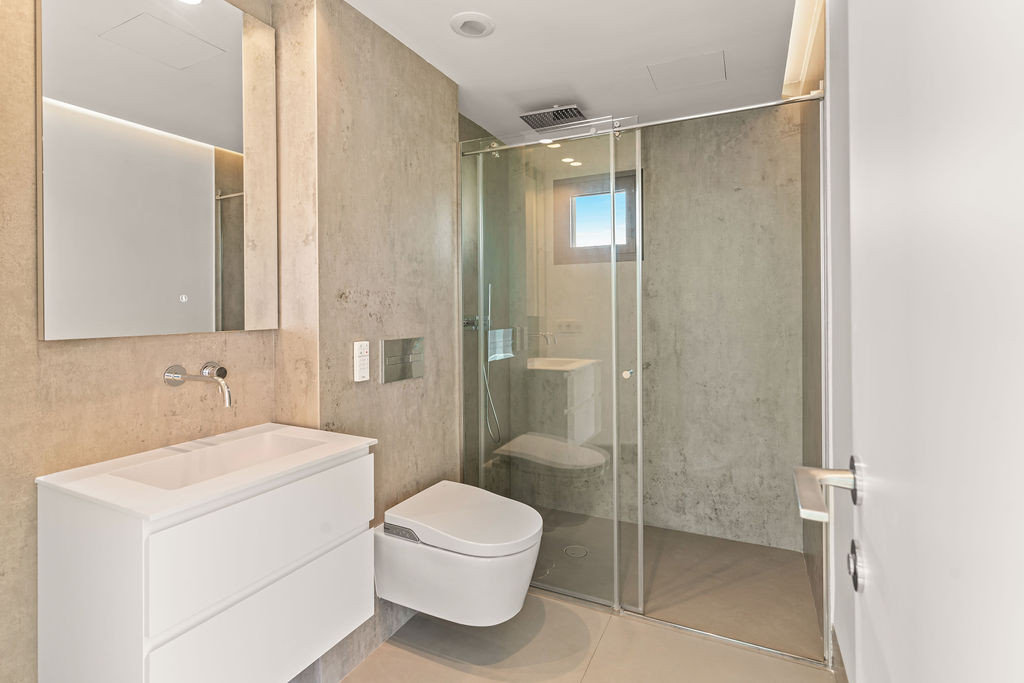 Modern bathroom with floating vanity, smart toilet, and large glass-enclosed shower.