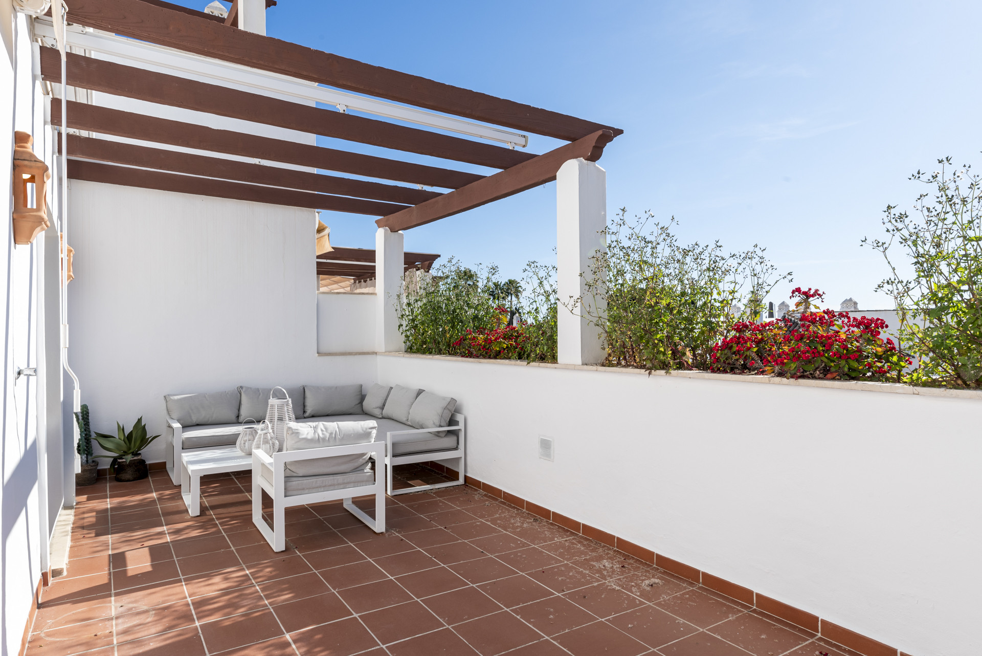 Terrace with white outdoor seating, a coffee table, and built-in planters with greenery.