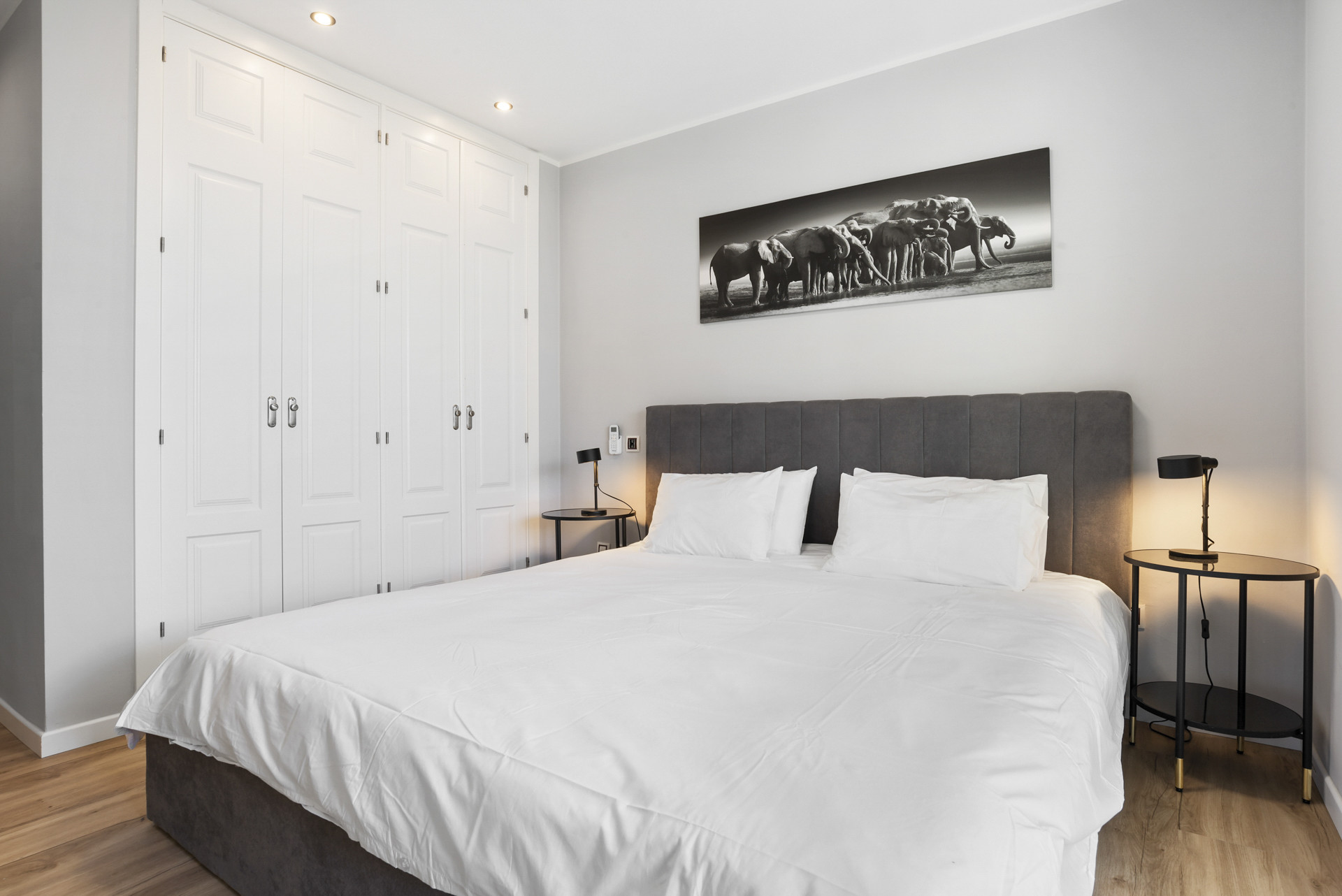 Bedroom featuring a large bed, gray headboard, bedside tables, and built-in wardrobes.