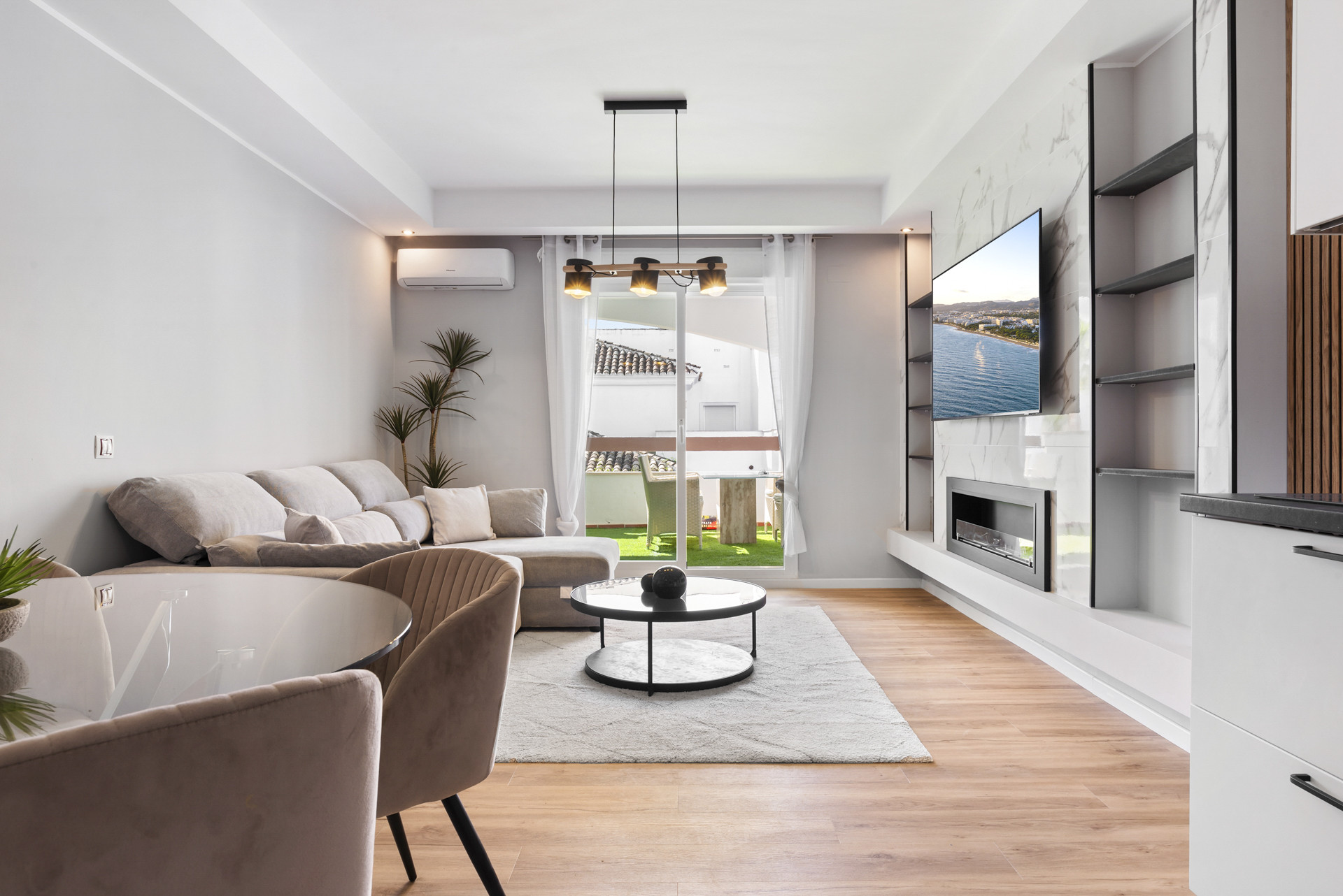 Living space featuring a sofa, dining table, and wall-mounted TV with coastal view.