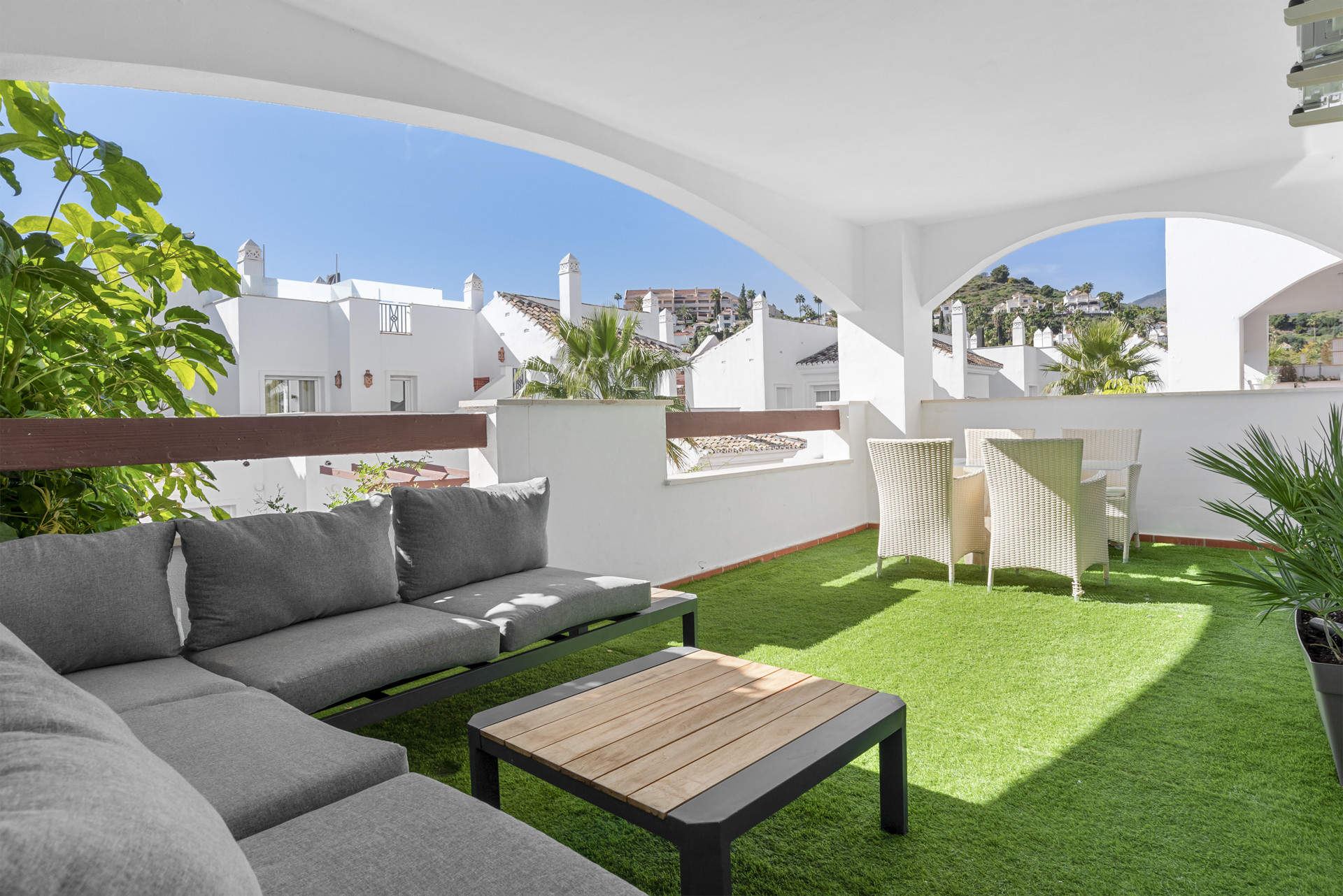 Outdoor terrace with seating and green landscaping.