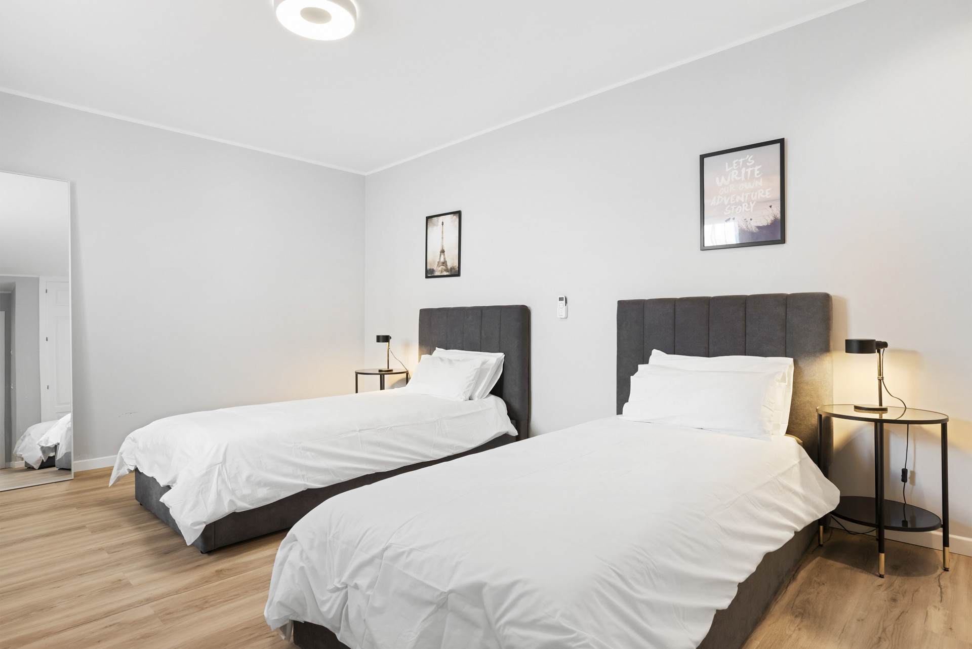 Second bedroom with two twin beds, bedside lamps, and framed wall art.