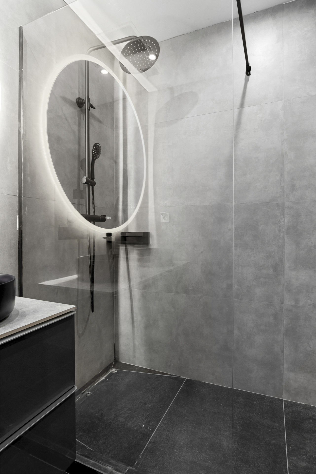 Shower area showing a rain shower head, round light, and glass wall.