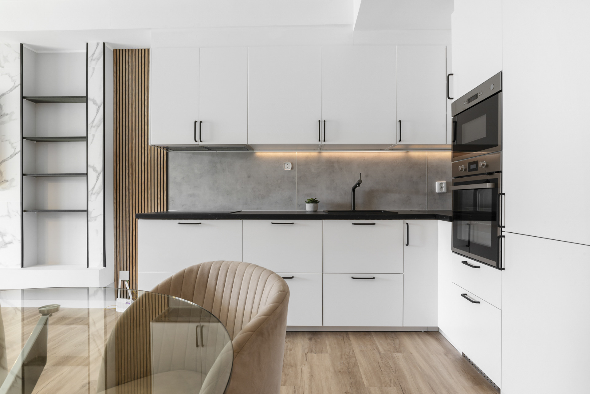 Modern kitchen with white cabinets, black countertop, and built-in appliances.