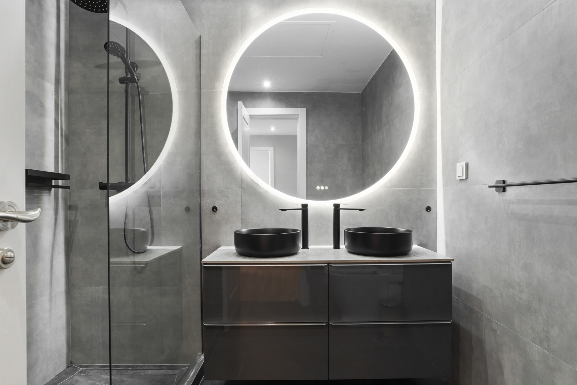Modern bathroom featuring round mirrors and sleek fixtures.