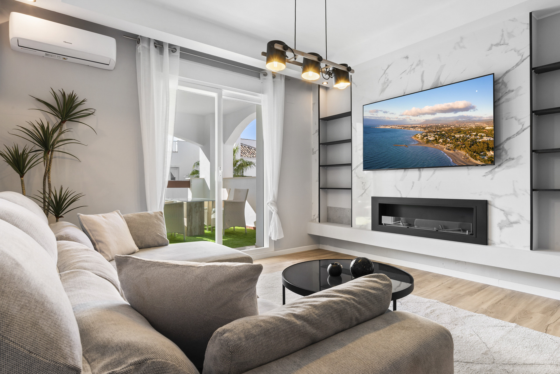 Bright living room with sofa, TV, and large glass door leading to a balcony.