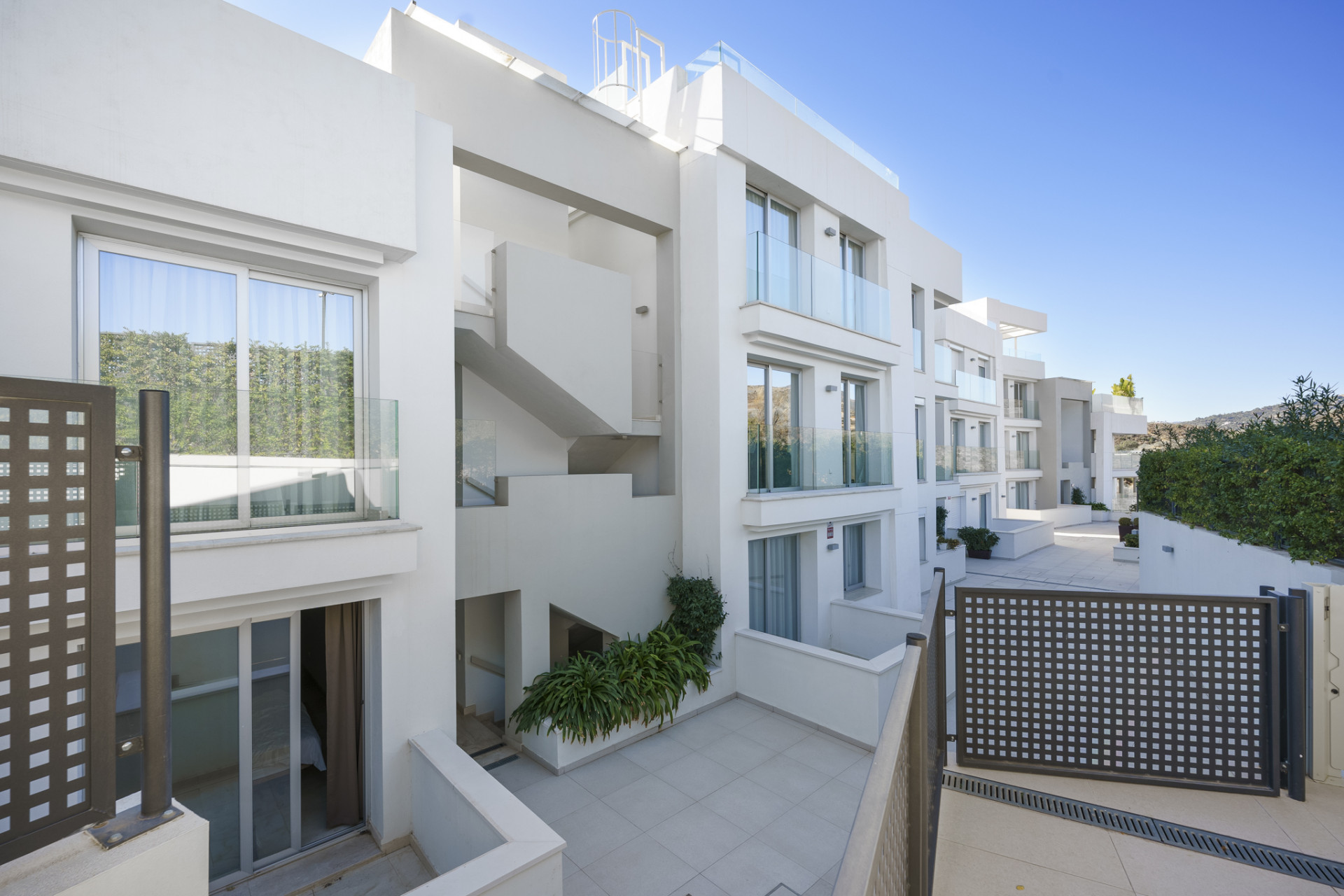 Exterior view of a modern building with balconies and greenery surrounding it.