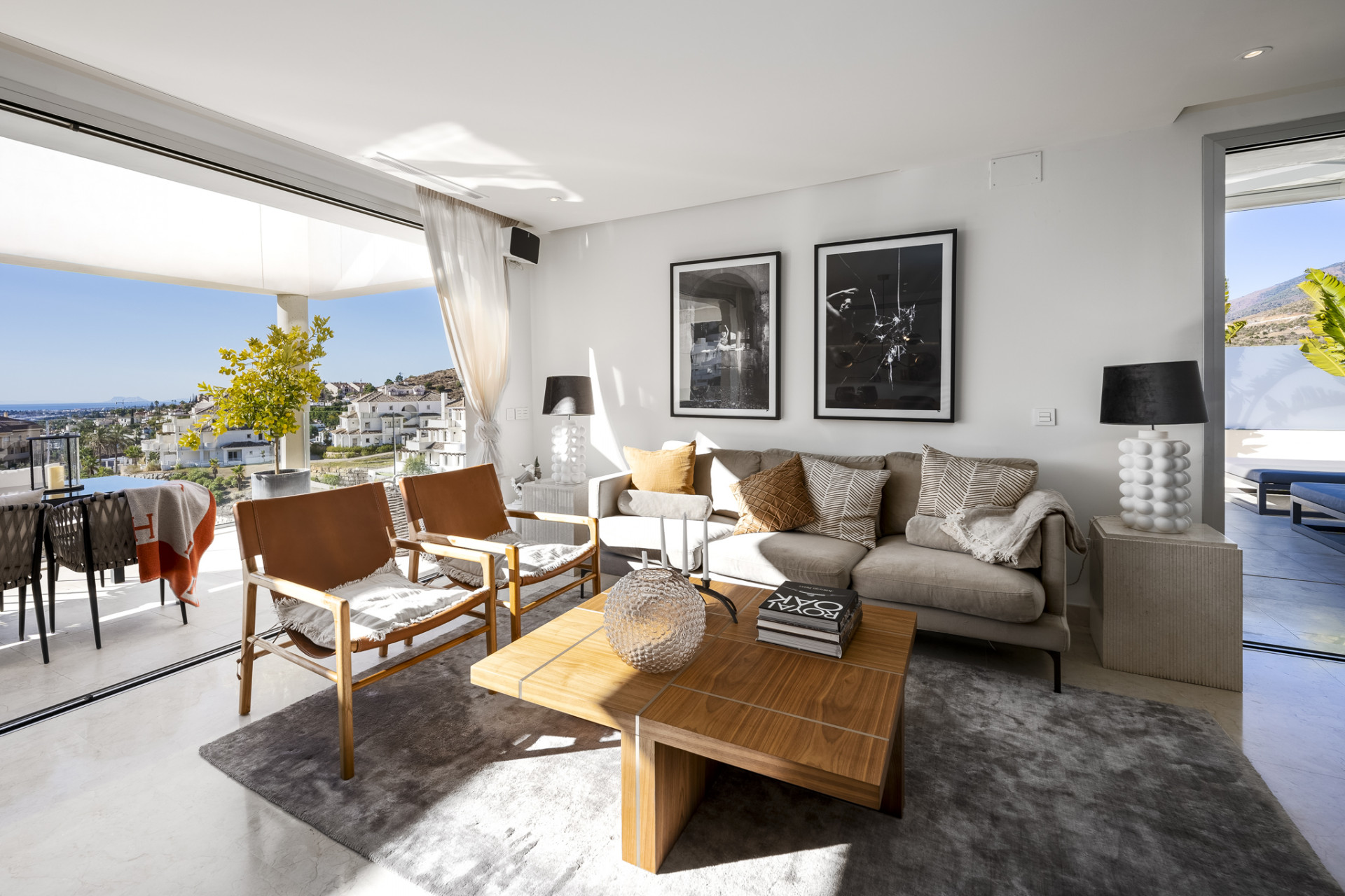 Bright living room with large windows and sea view. Contemporary furniture and decor present.