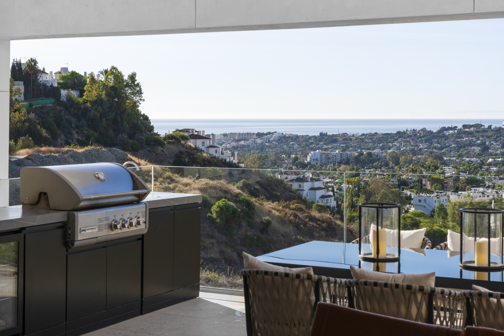 Outdoor kitchen with BBQ grill and dining area overlooking the hillside and ocean.