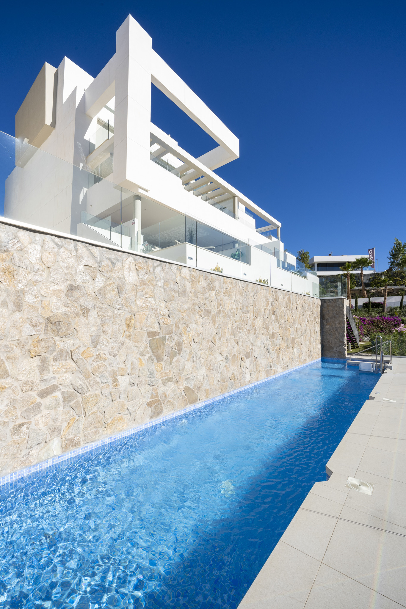 View of the modern penthouse exterior with a pool and stone wall.