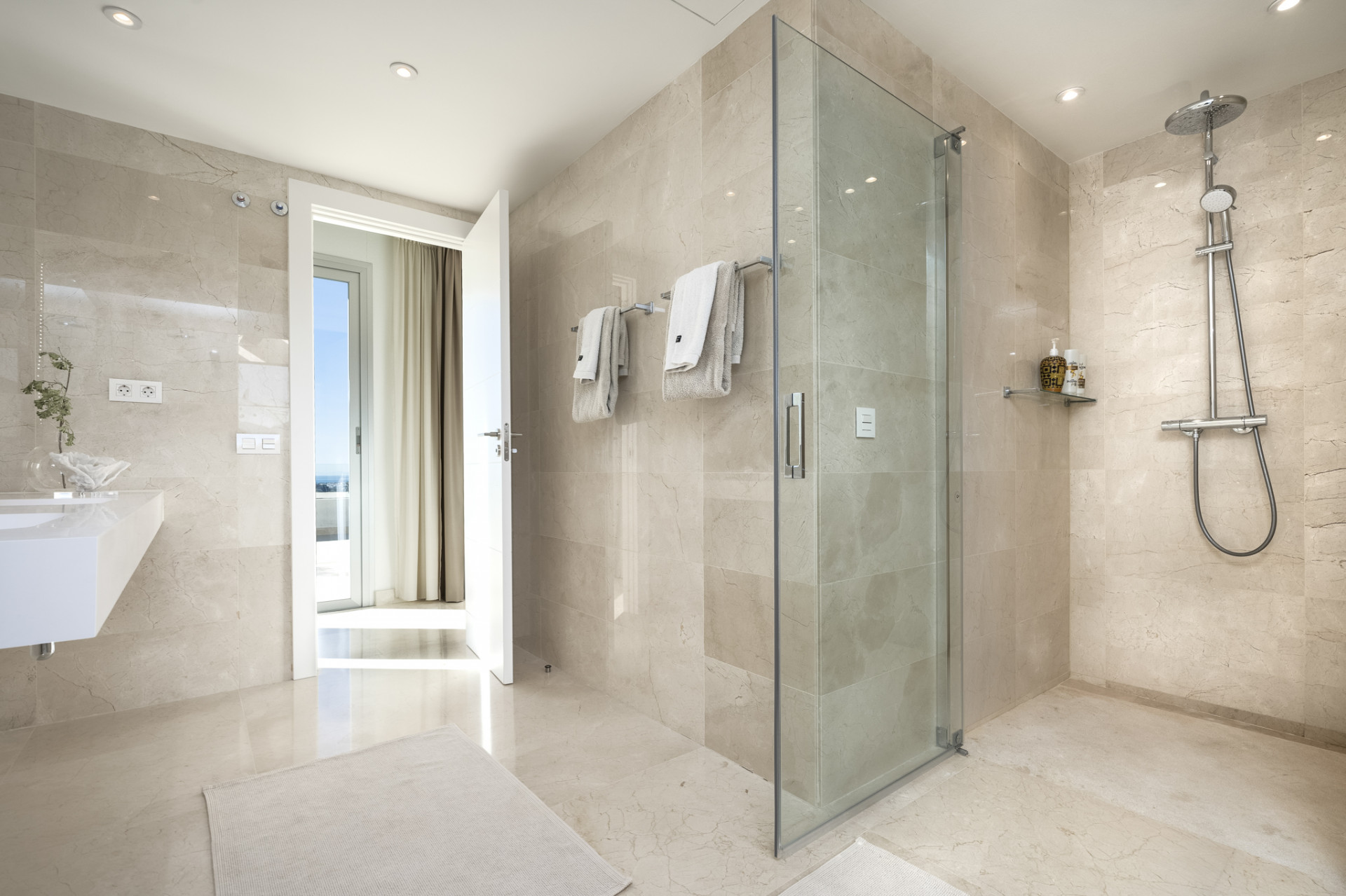 Modern bathroom featuring a shower, sink, and light-colored tile finishes.