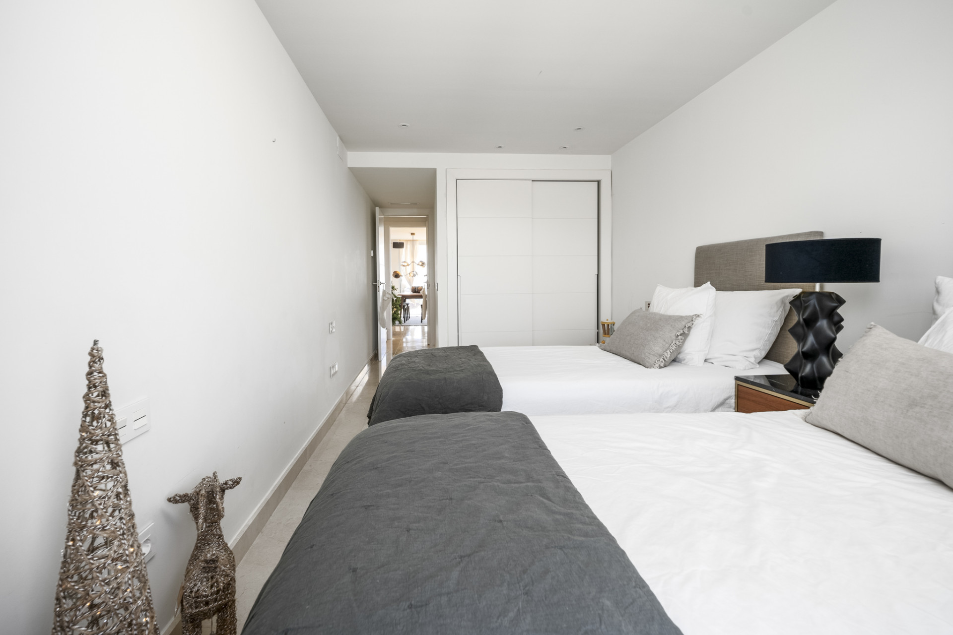View of the bedroom from the back showing twin beds and unique decorative figures.