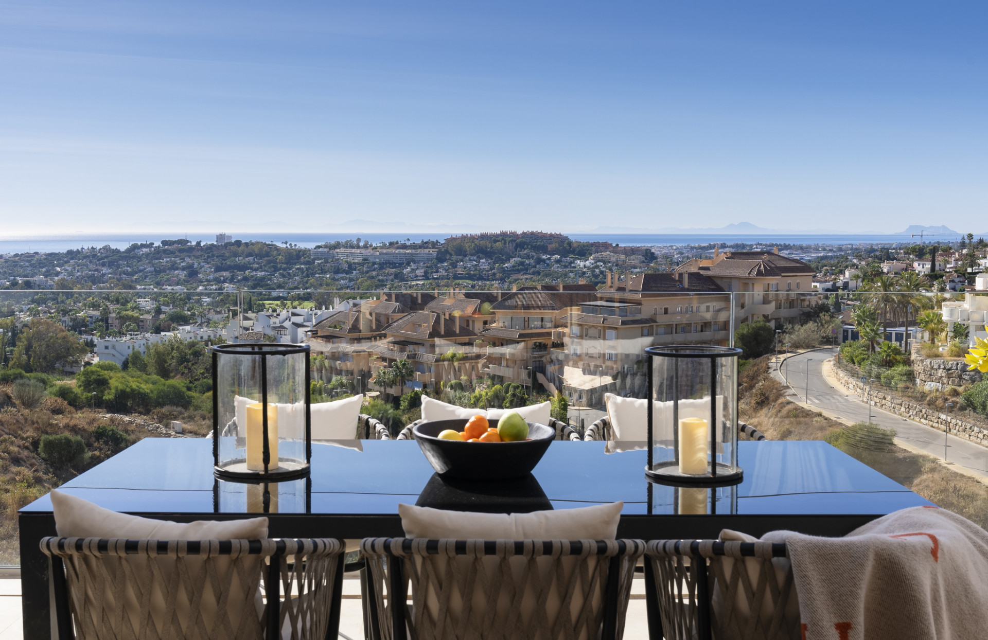 Balcony view with a table set against a coastal backdrop