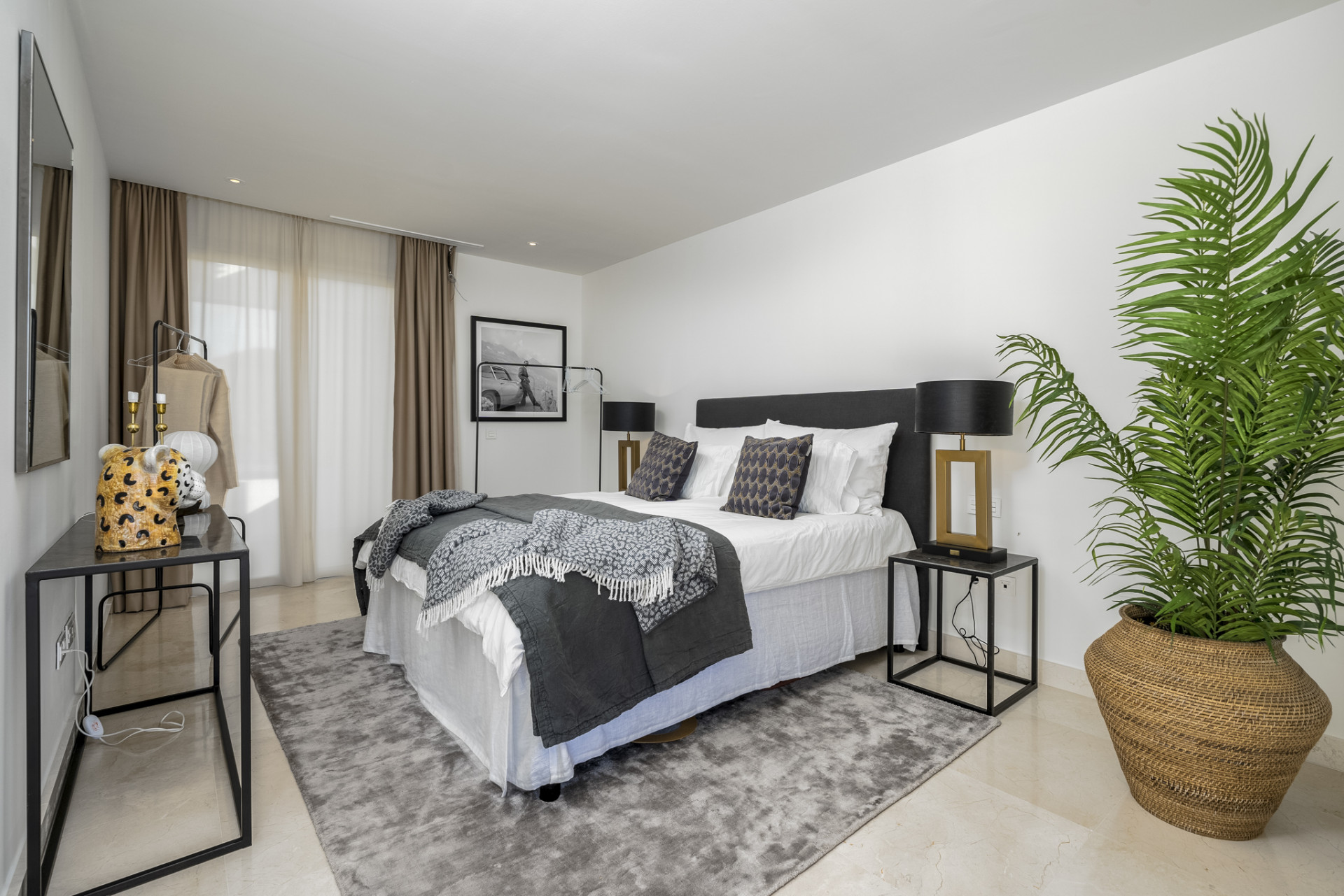 Cozy bedroom with a large bed, decorative pillows, and a green potted plant.