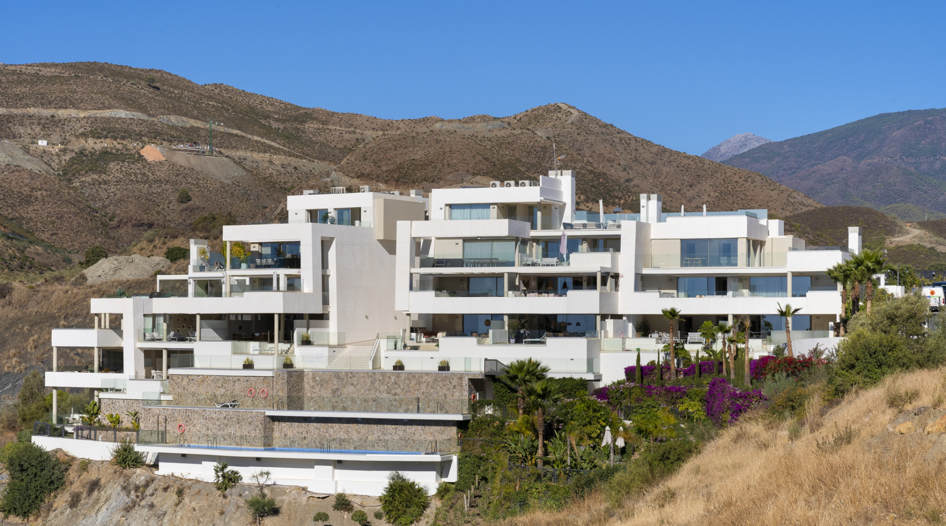 Exterior view of a modern building complex set against mountainous terrain.