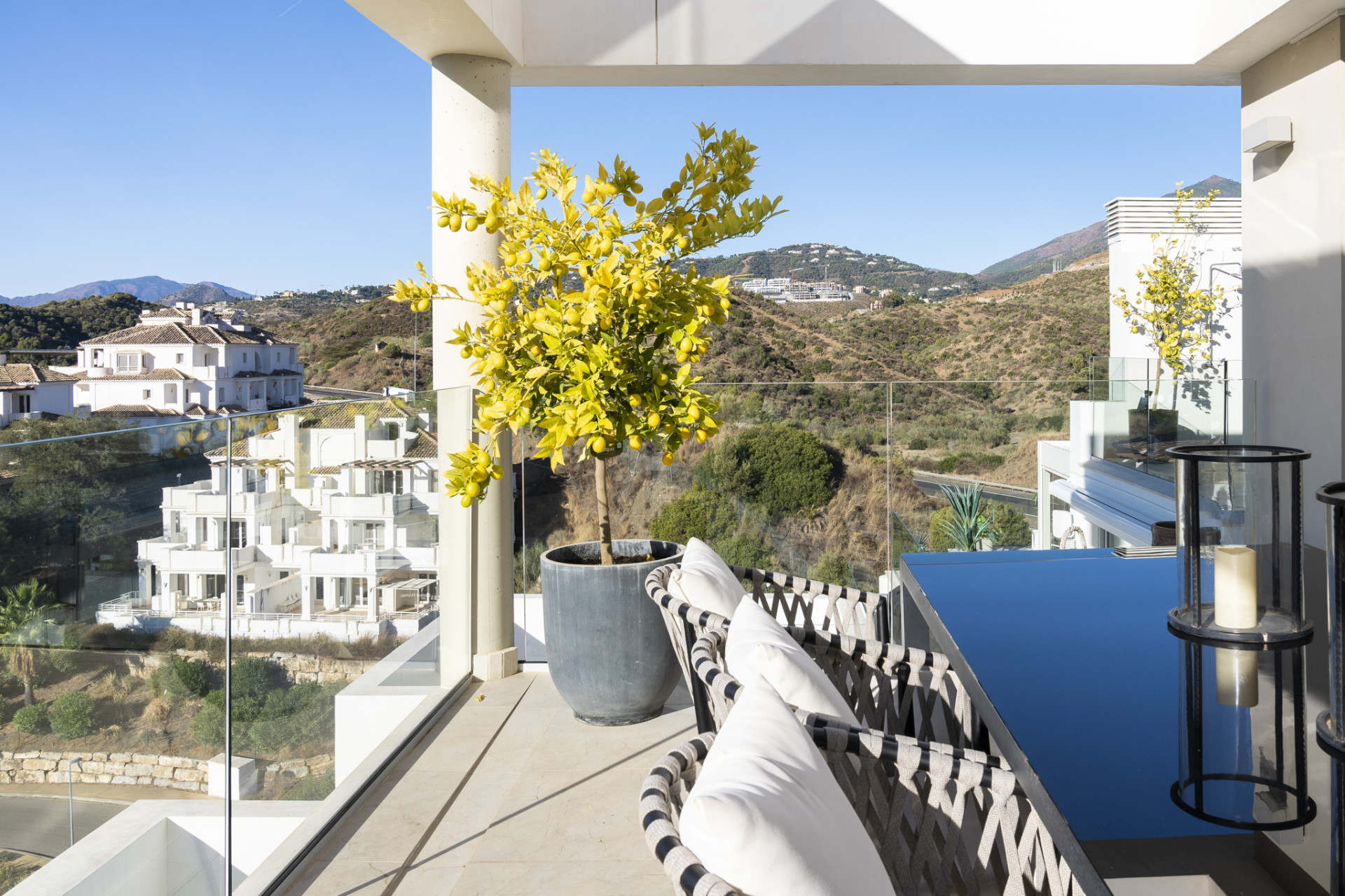 Covered balcony with seating and a view of the hills and other properties.