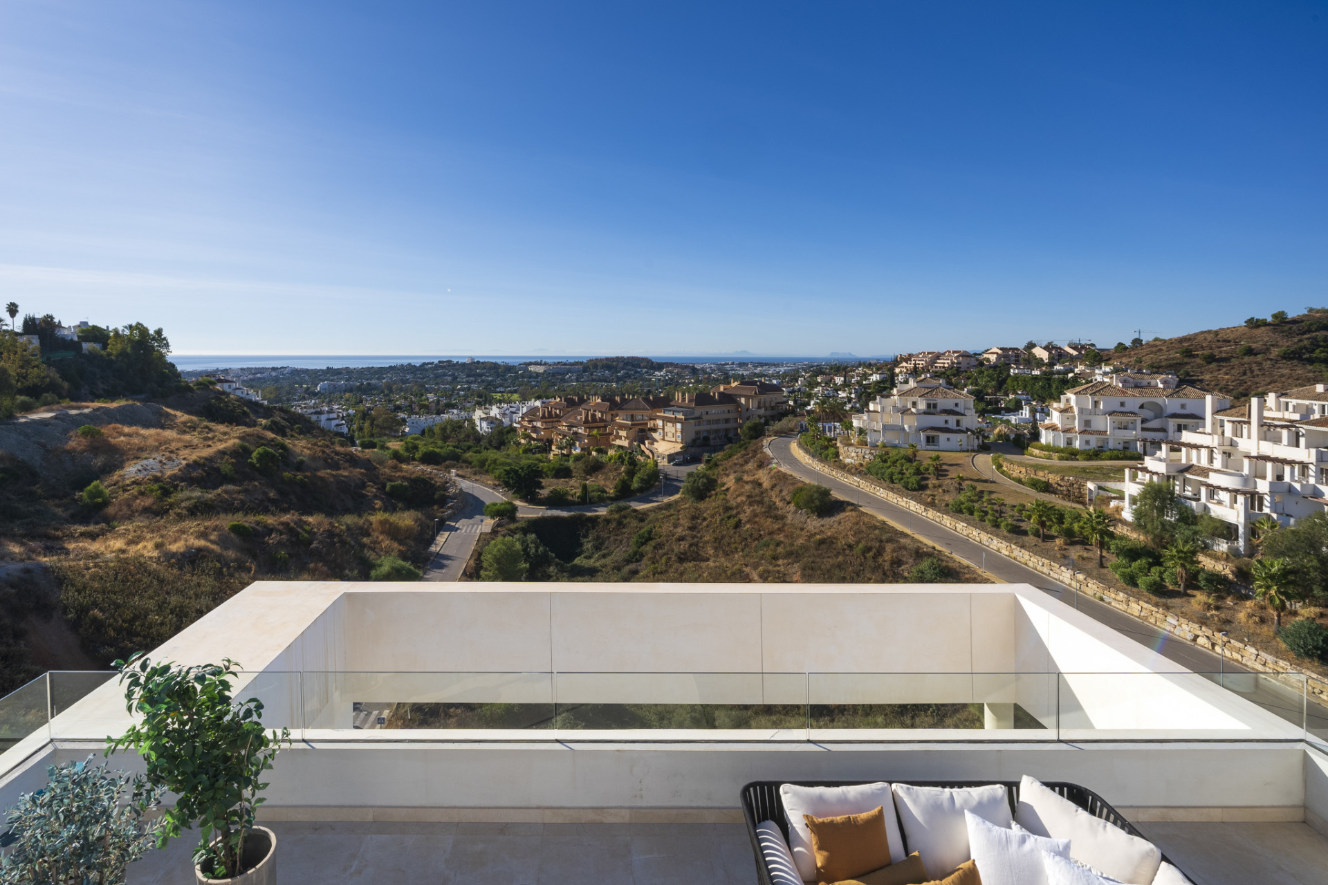 View from the terrace showing hills, coastline, and a clear blue sky.