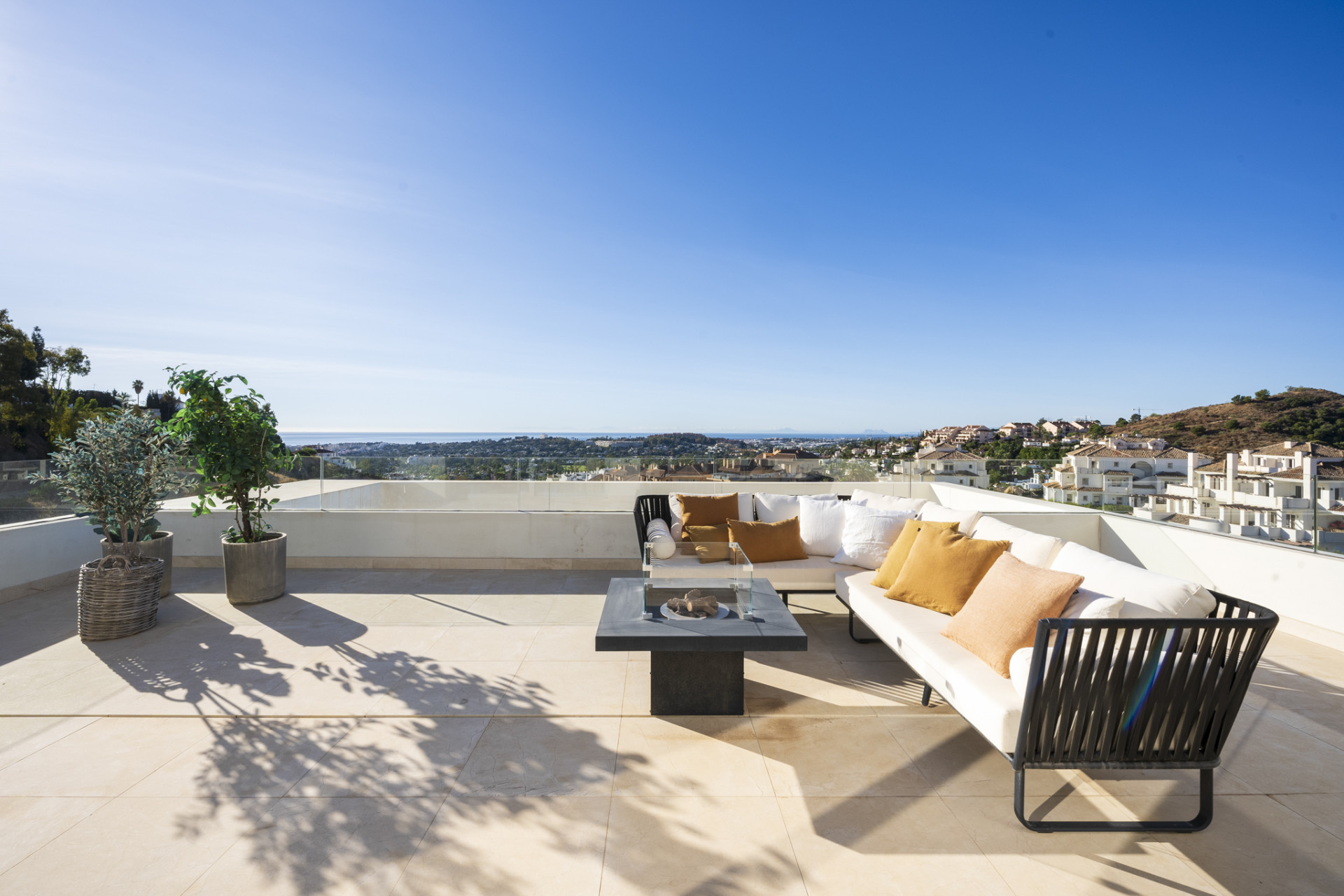 Spacious terrace with seating, plants, and a table overlooking the view.