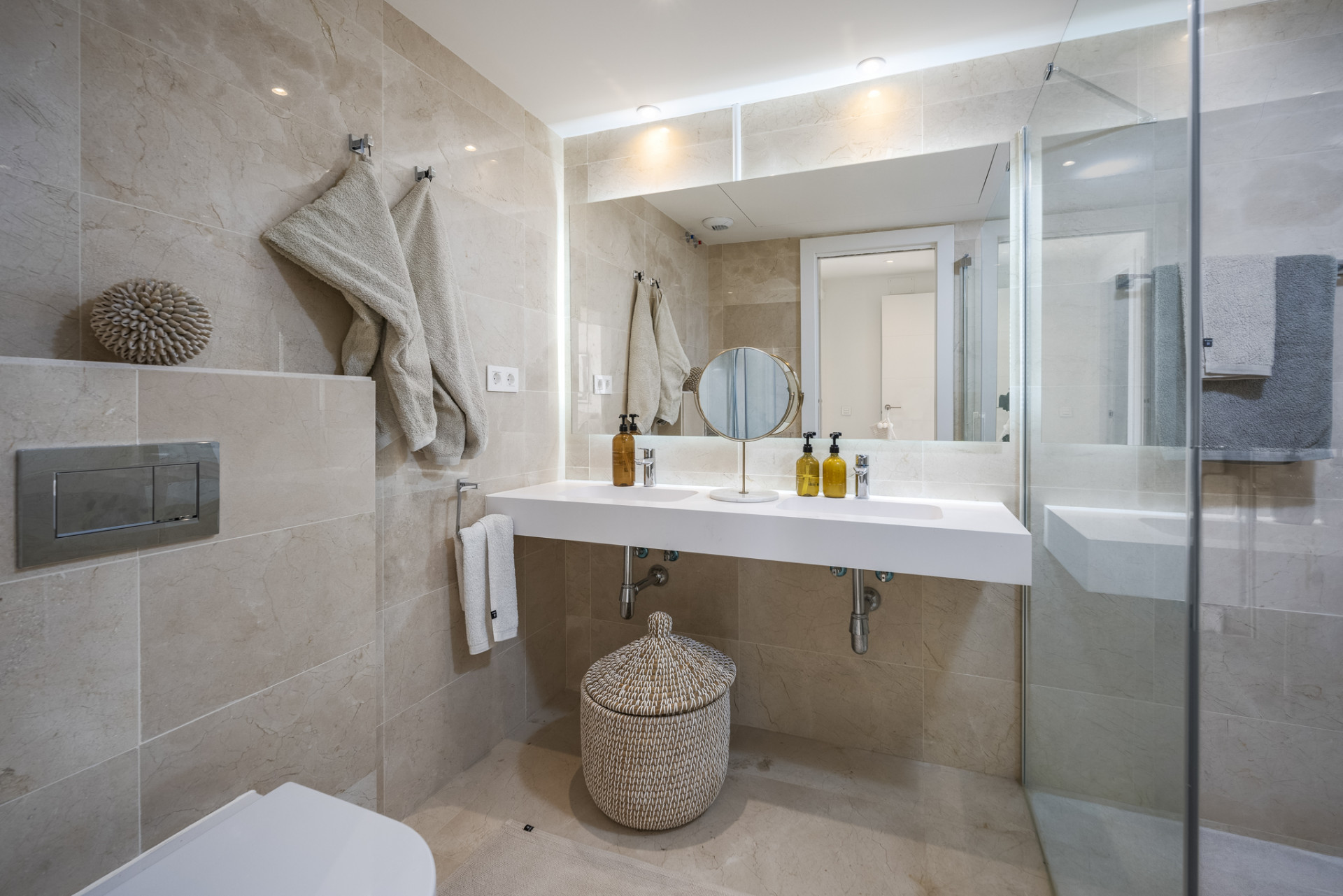 Stylish bathroom featuring stone walls, double vanity, and a glass shower enclosure.