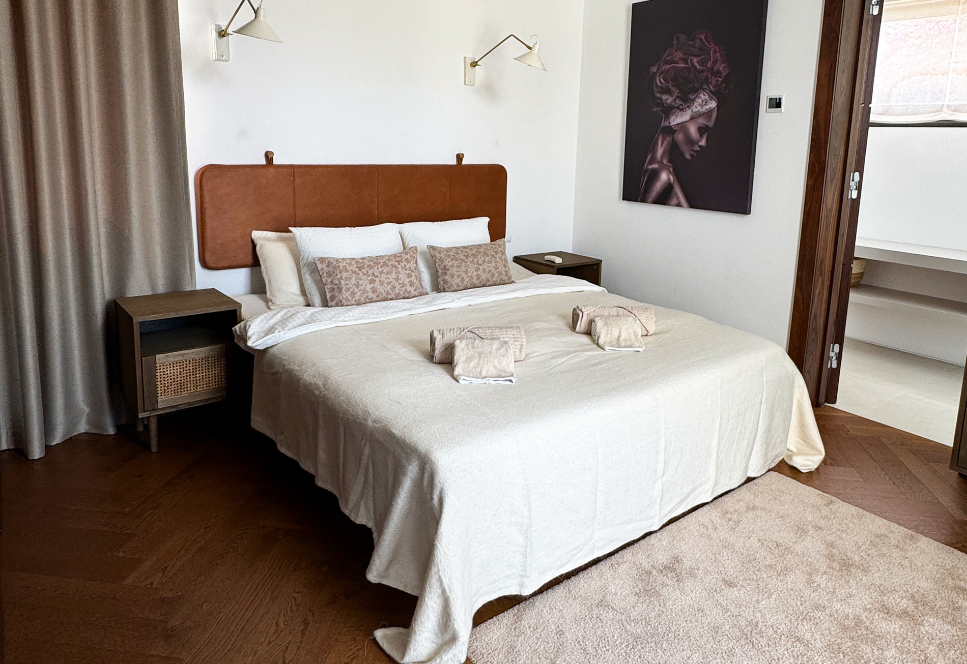 Bedroom with a queen bed, leather headboard, two nightstands, and dark art on the wall.