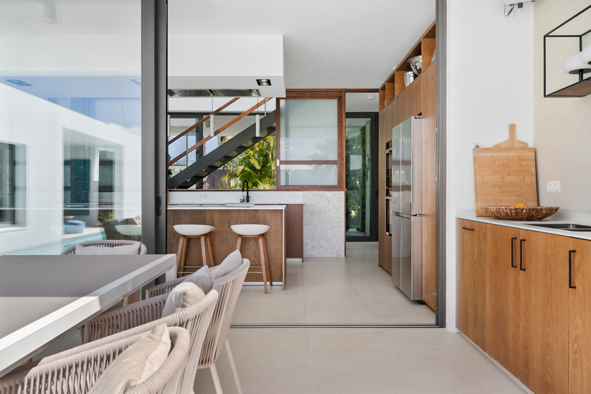 Kitchen and dining area with wood cabinetry, a large refrigerator, breakfast bar, and visible staircase.