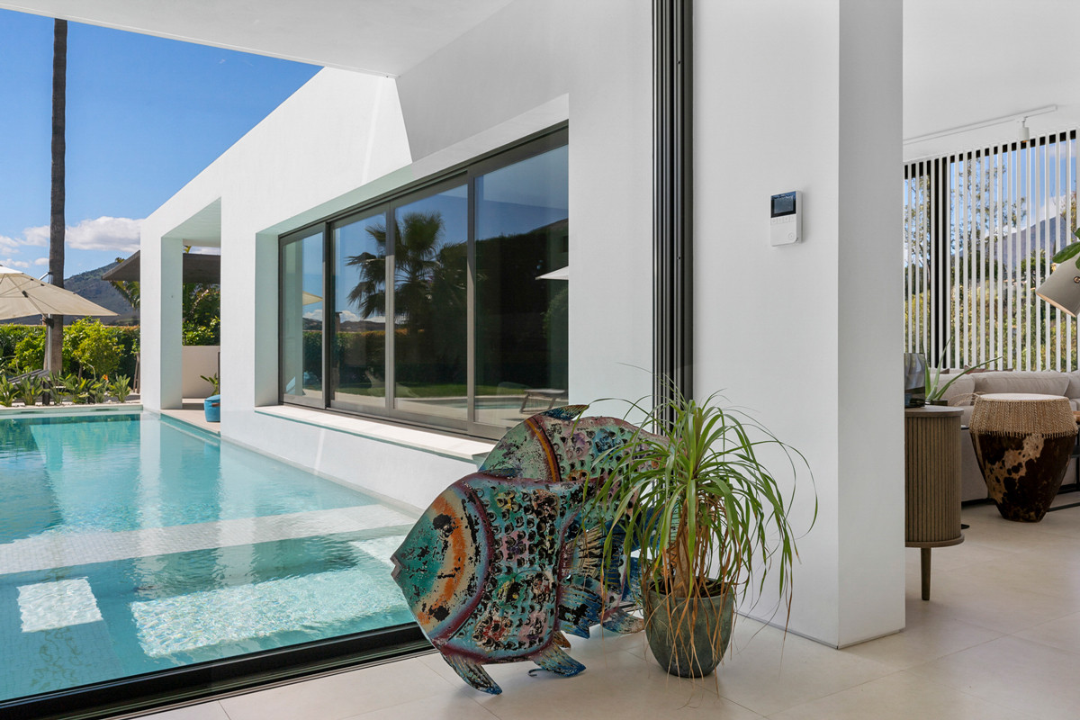 Outdoor view of a swimming pool with large decorative fish art next to a glass sliding door.