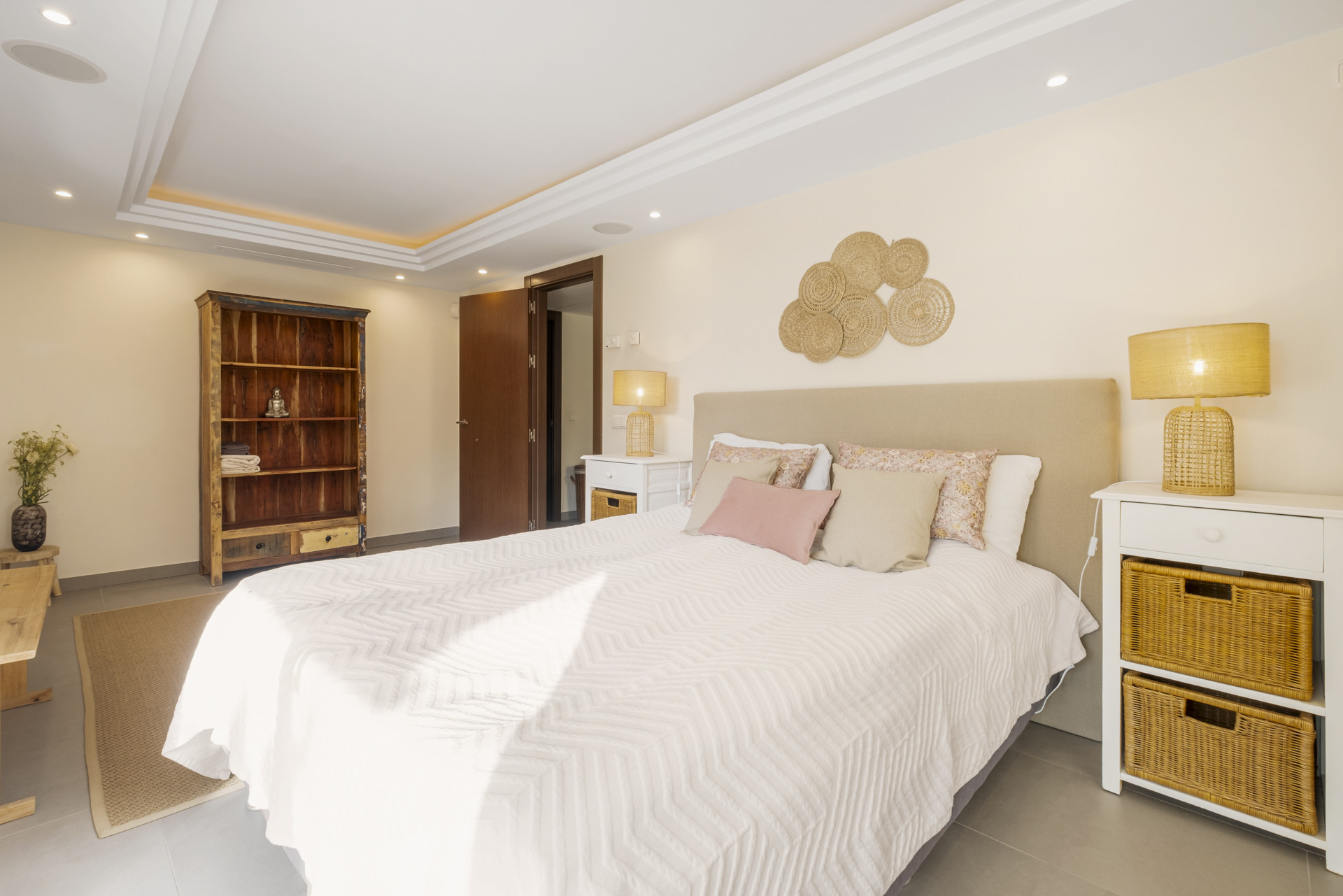 Bright bedroom featuring a wooden shelf and soft decorative accents on the bed.