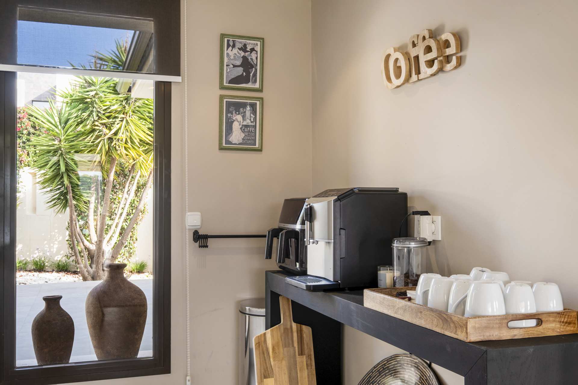 Coffee station with espresso machine, cups, and decorative elements visible through the window.