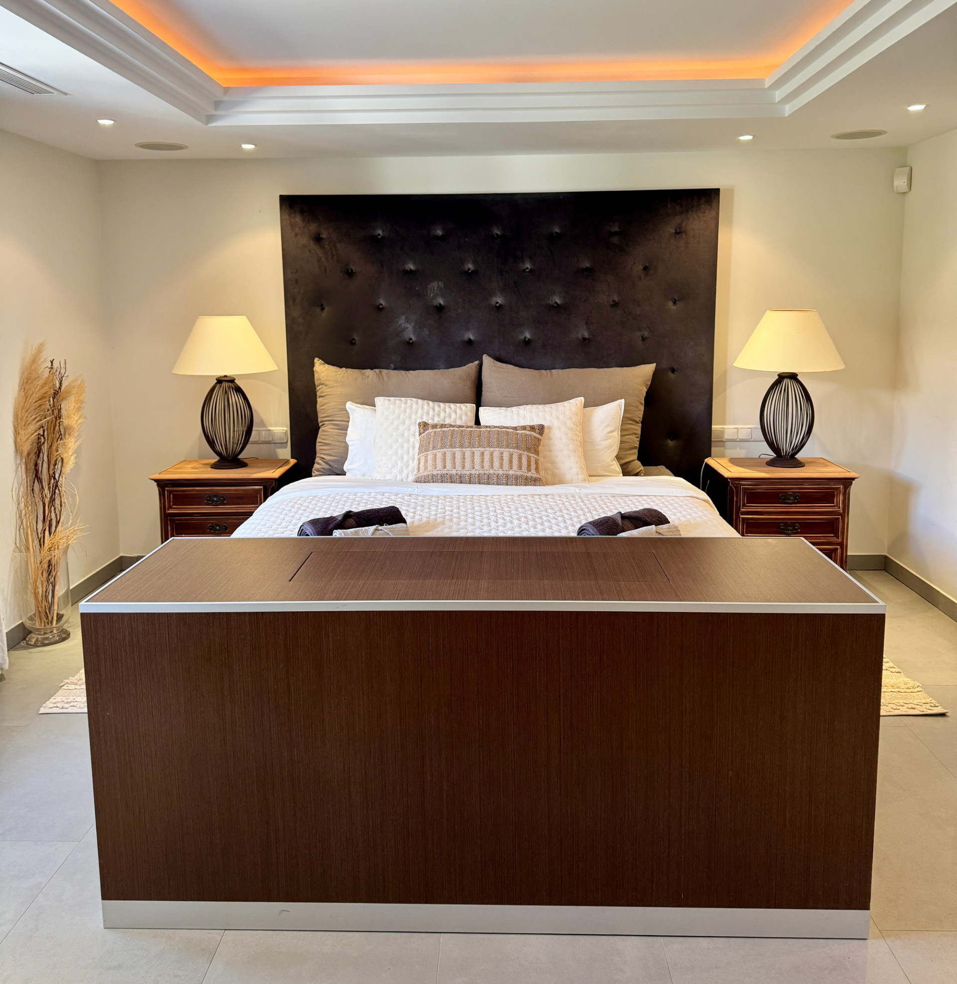 Another view of the bedroom, emphasizing the large headboard and light fixtures.