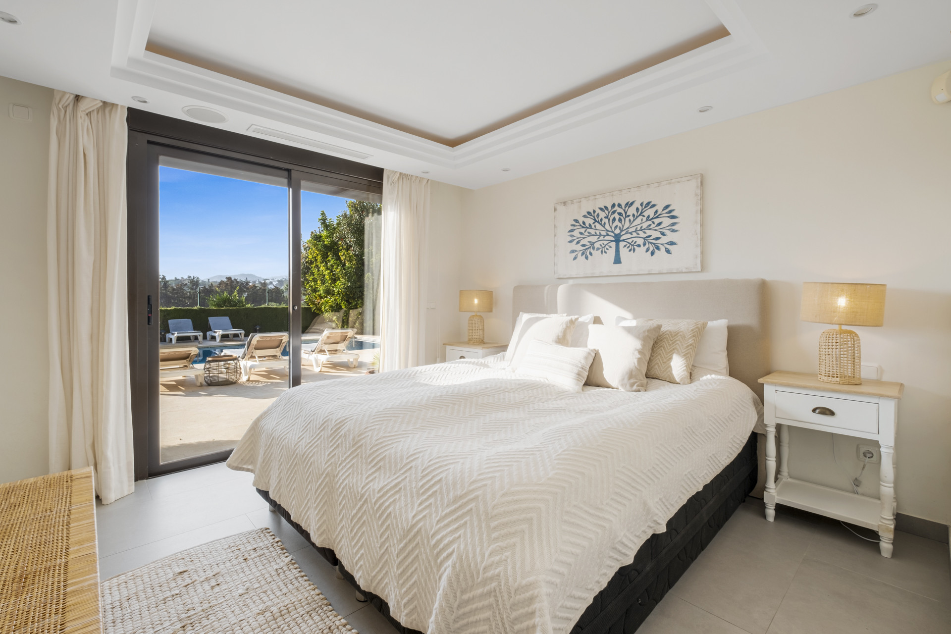 Spacious bedroom with a king-size bed, large windows, and a view of the pool area.