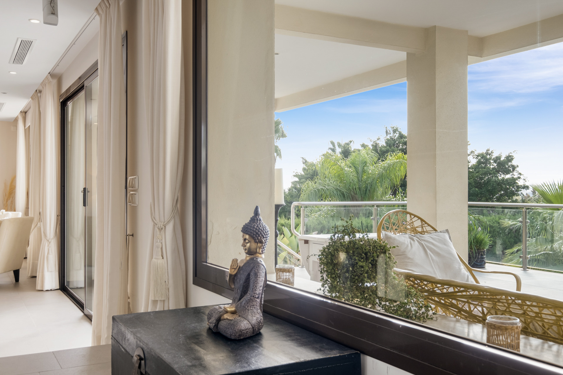 View of a sitting area with a Buddha statue and greenery outside, creating a serene atmosphere.