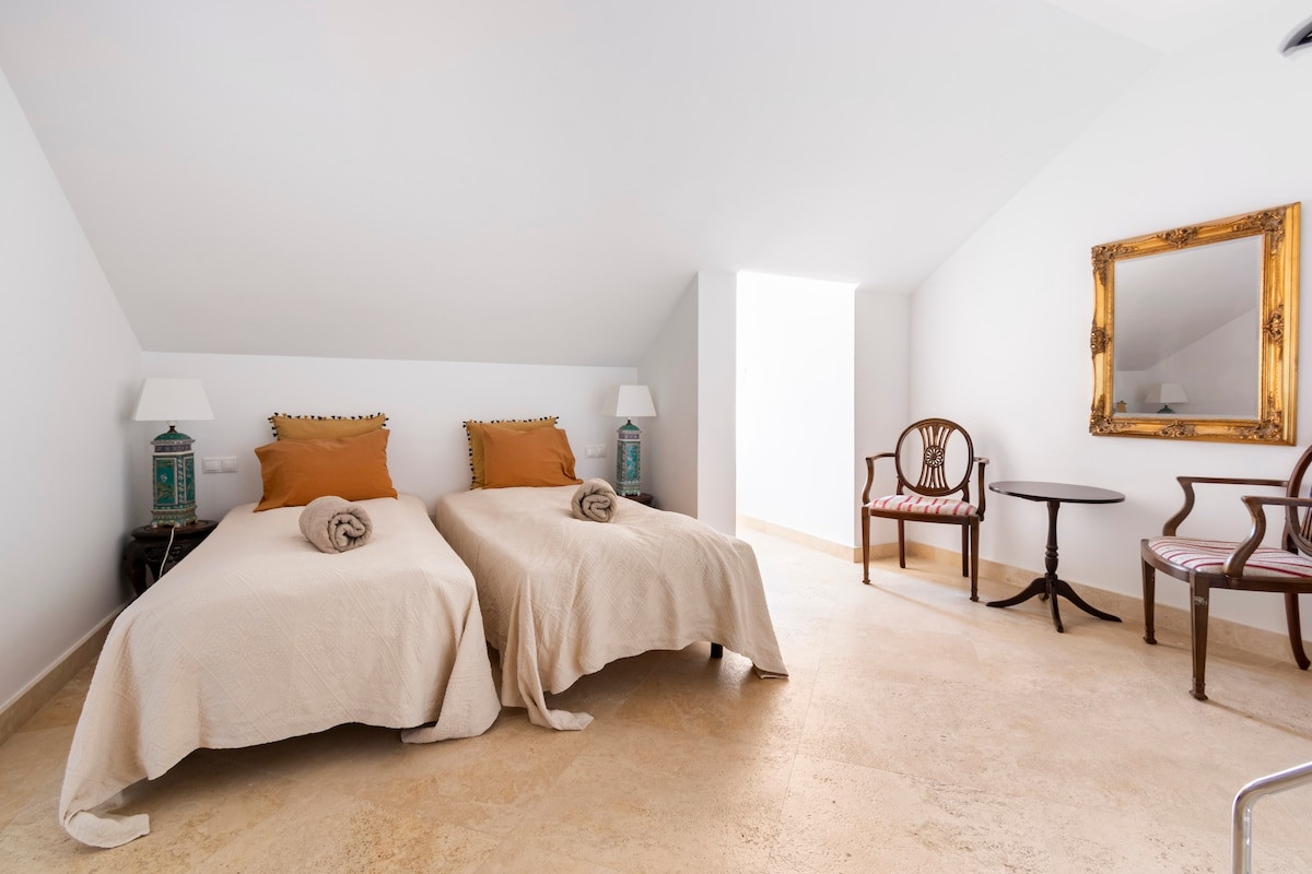 Guest bedroom with twin beds and decorative lamps on either side.