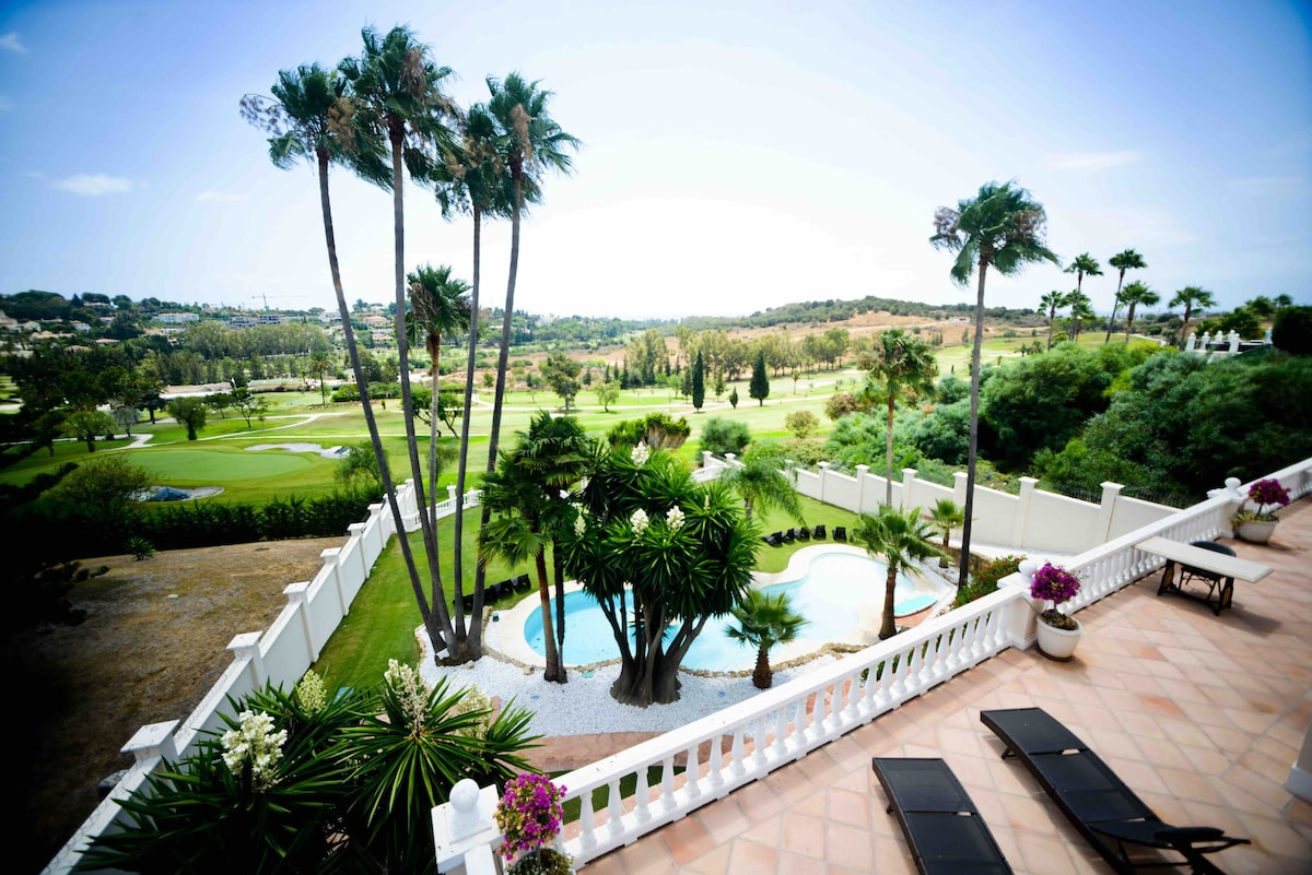 View from balcony showing palm trees and swimming pool overlooking golf course.