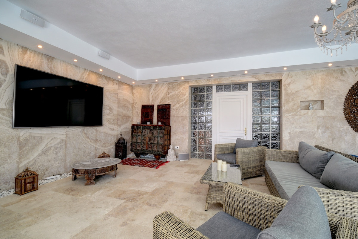 Modern lounge area with a mounted TV and textured stone walls.