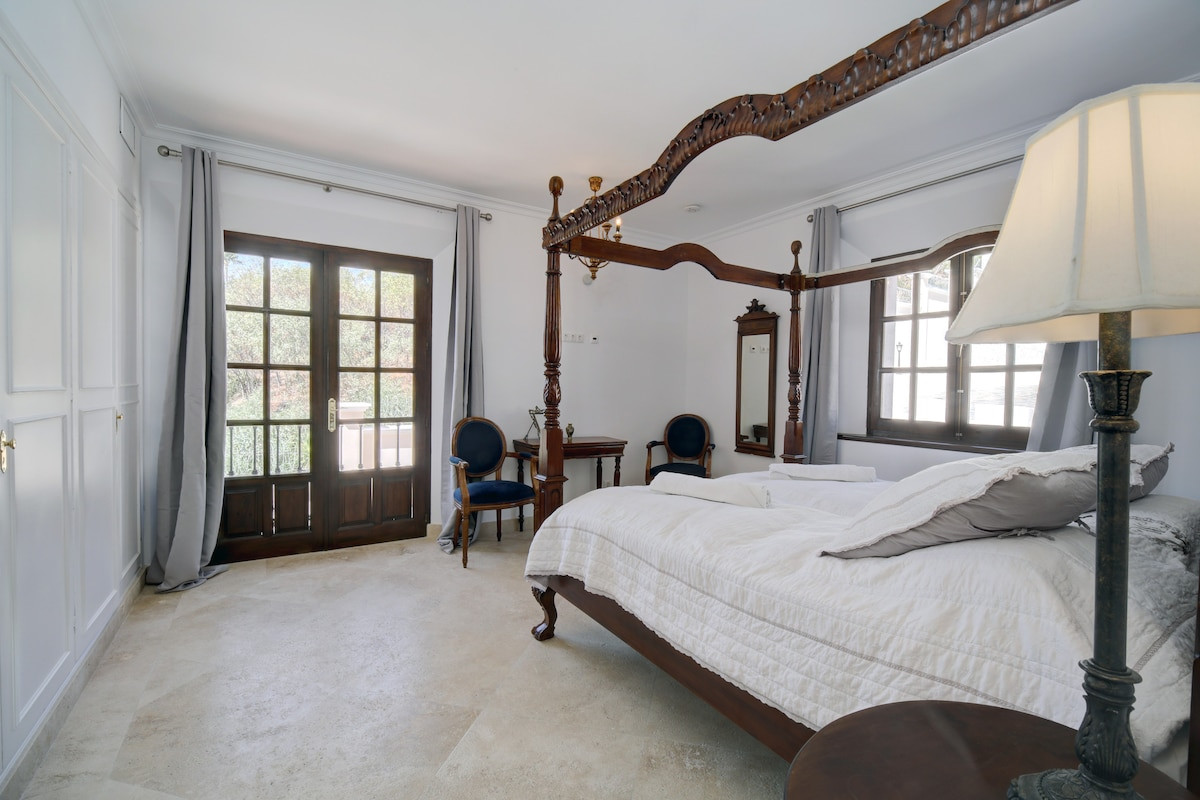 Master bedroom featuring a four-poster bed and wooden doors to the terrace.