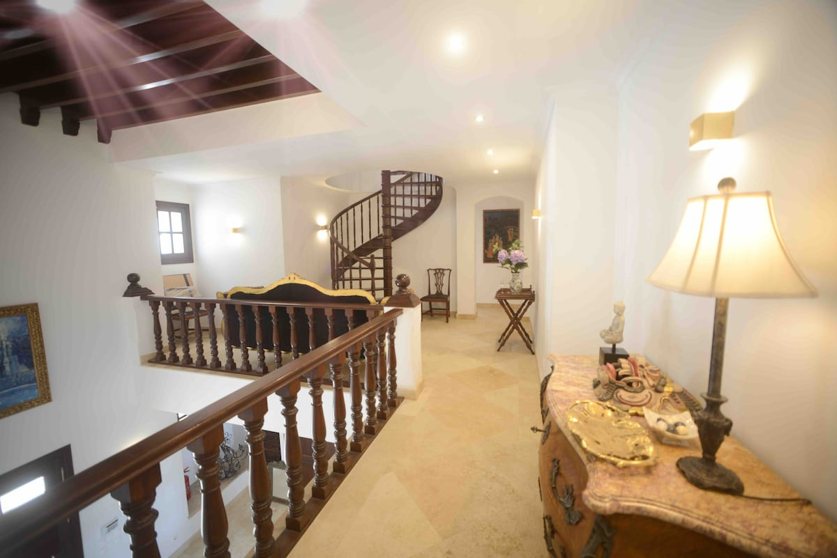 Second floor landing with wooden railings, a spiral staircase, and light fixtures.