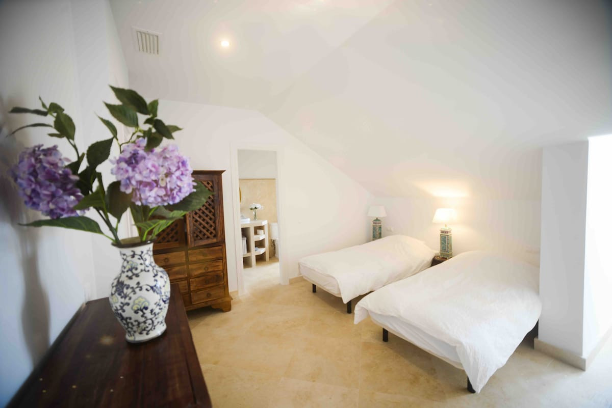 Bedroom with two single beds, decorative flowers, and access to an en-suite bathroom.