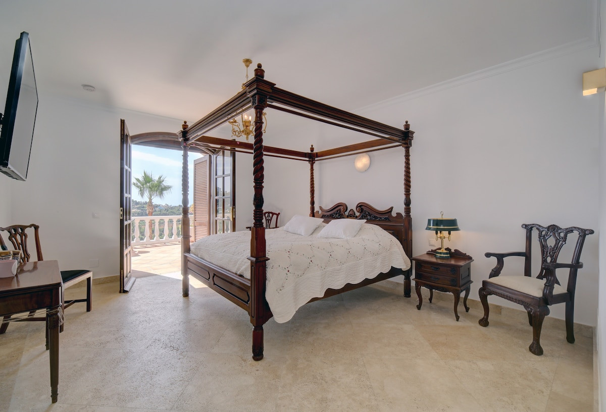 Elegant bedroom featuring a four-poster bed and a nightstand with a lamp.