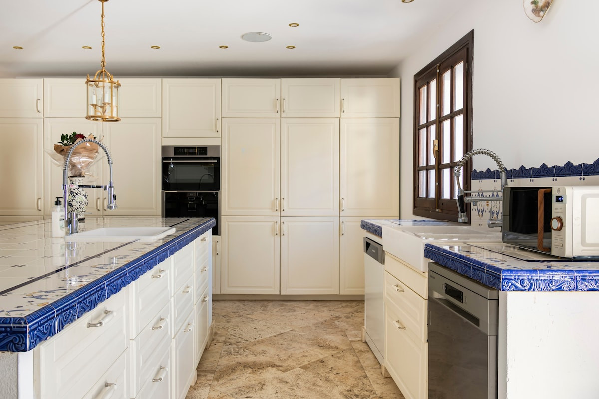 Modern kitchen with white cabinetry, blue tile countertops, and stainless appliances.