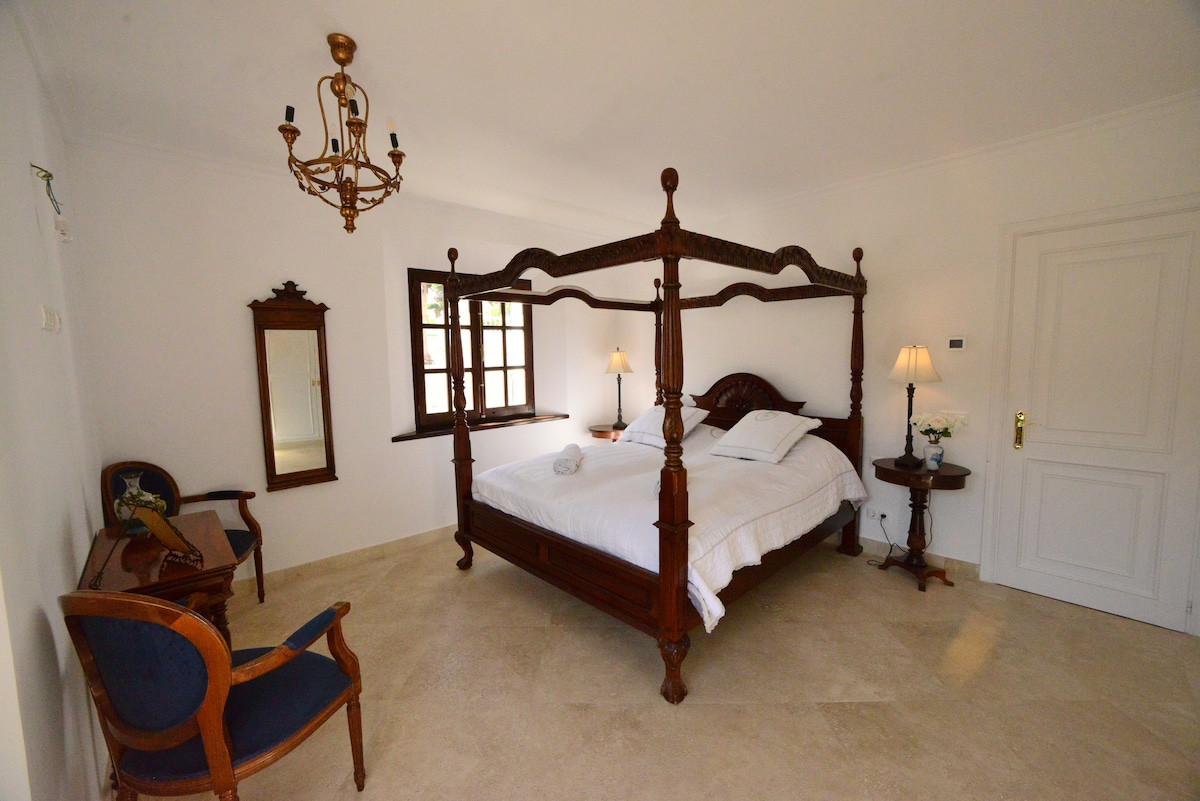 Bedroom with a four-poster bed and antique furniture, featuring a chandelier.