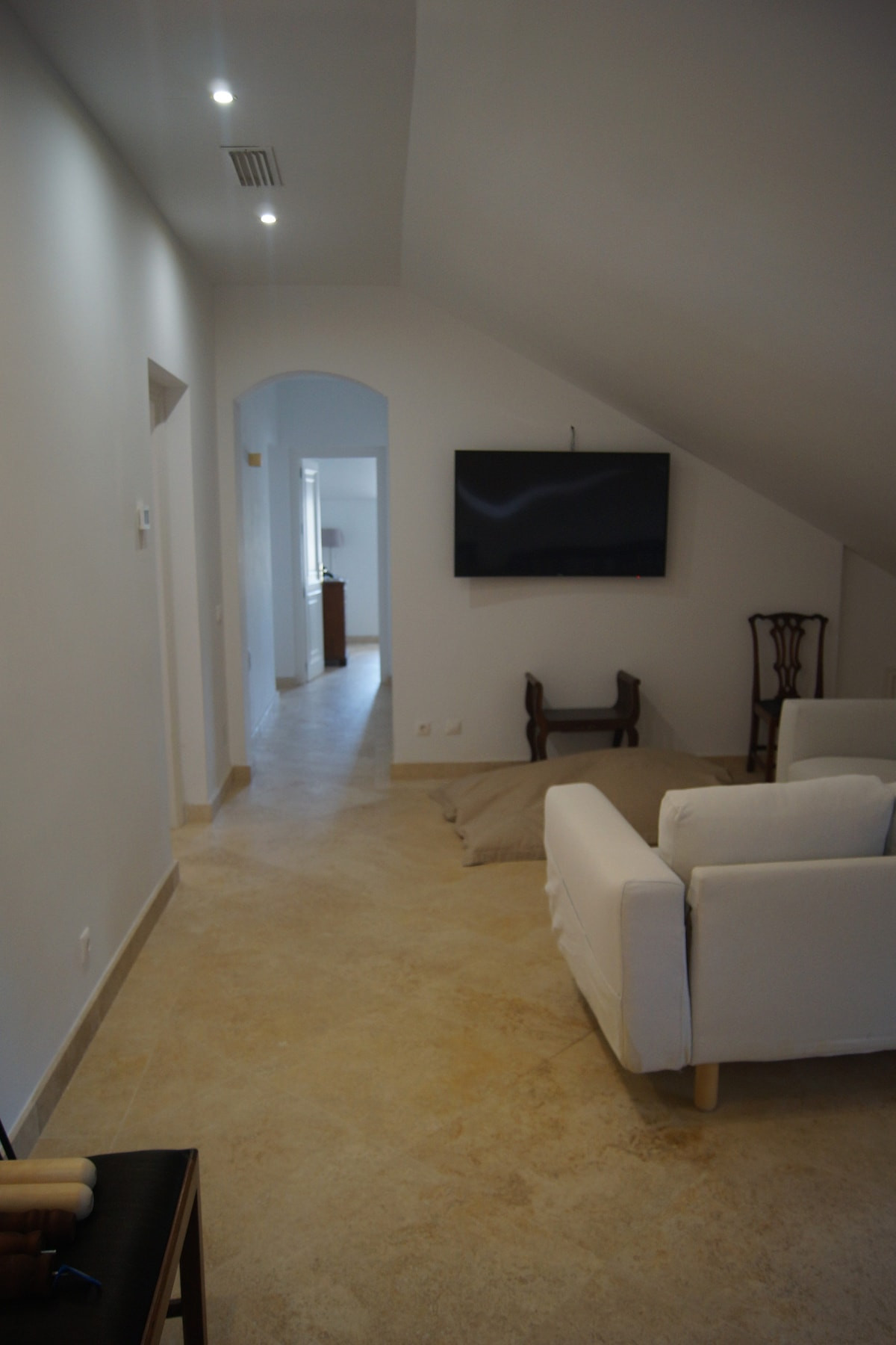 Hallway with a flat-screen TV, light-colored walls, and seating arrangement.