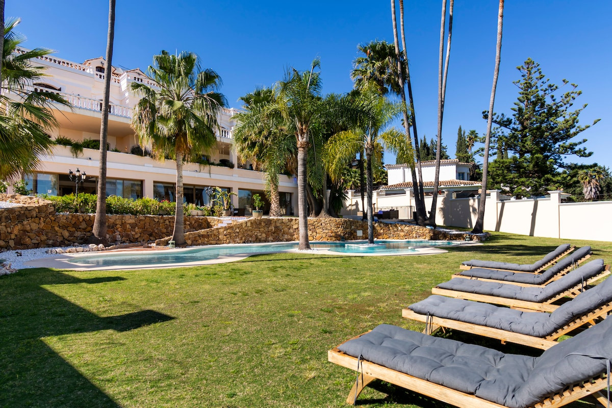 Exterior view with loungers, palm trees, and a pool at a luxury property.