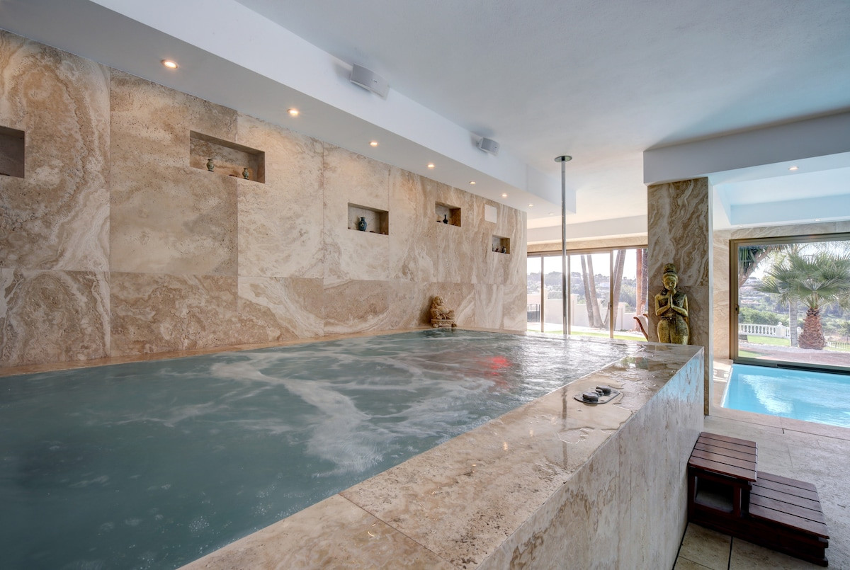 Spa area featuring a stone wall and a Buddha statue beside a pool.