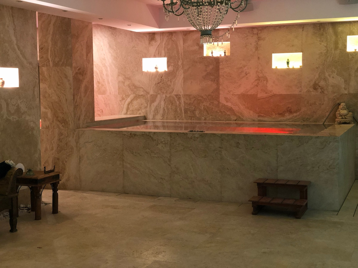 Indoor pool area with marble walls and soft lighting, featuring a decorative chandelier.