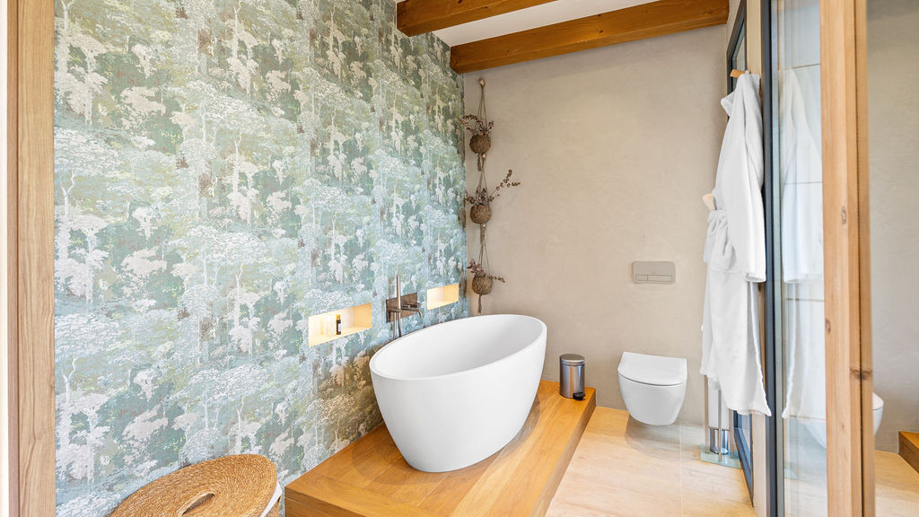Modern bathroom with a freestanding tub and patterned wallpaper.