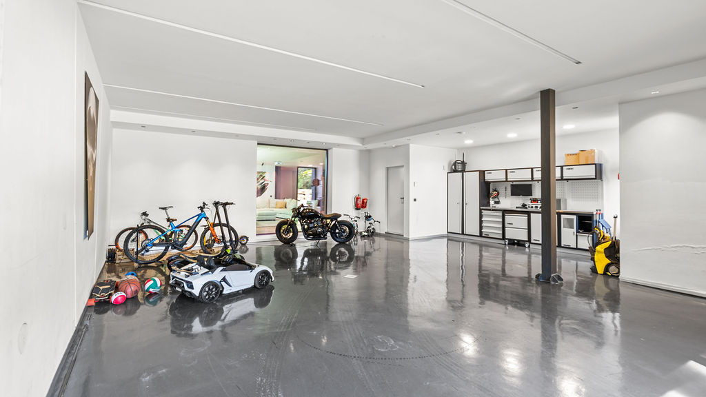 Spacious garage area with bicycles, toys, and storage units.