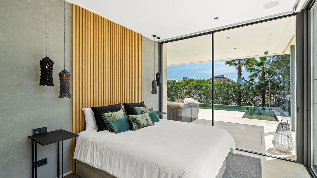 Modern bedroom with large glass doors and palm view.