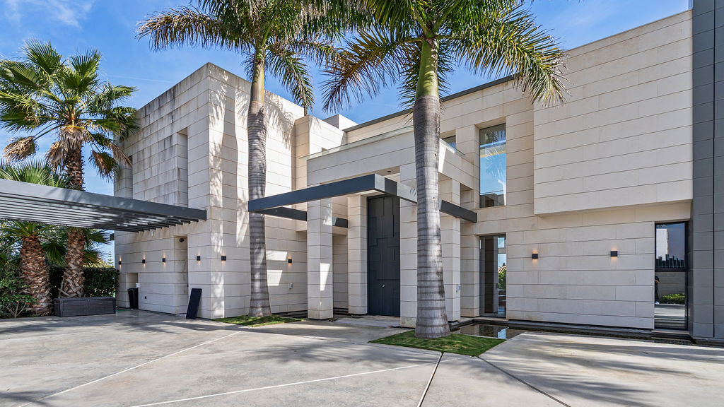 Close-up of the modern entrance with palm trees and decorative lighting.